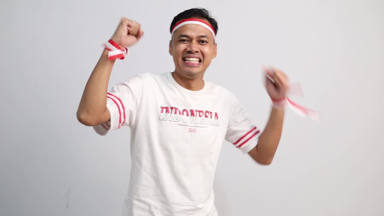 Giovane uomo asiatico con le mani giunte, celebra il giorno dell'indipendenza dell'Indonesia, isolato su sfondo bianco.