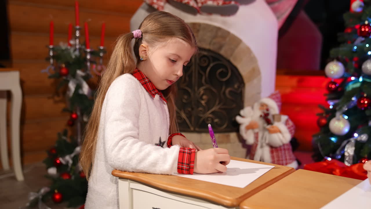 Children painting at Christmas decorated room. Cute little girls sitting on floor and drawing pictures on small desks for Santa. Christmas spirit