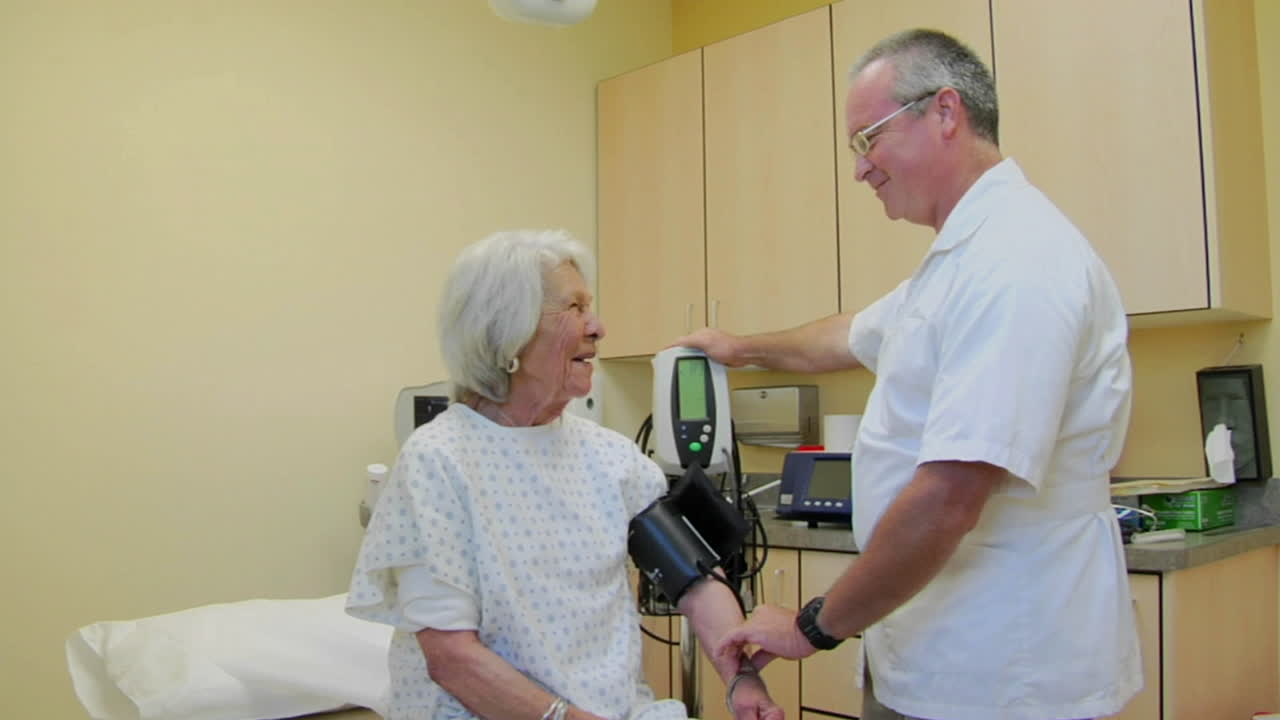 의료 전문가는 노인 환자의 혈압을 측정합니다.