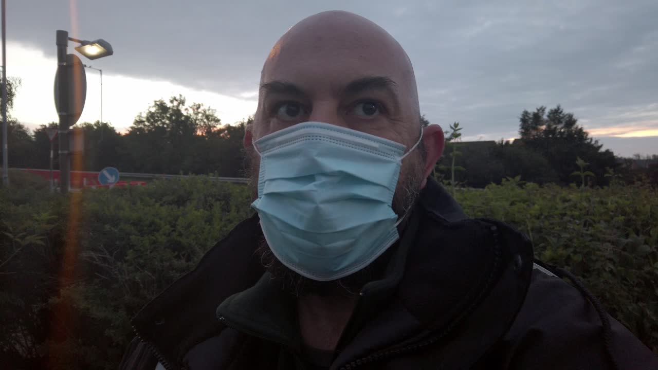 hombre en el lugar de trabajo con uniforme ajusta la máscara facial ppe contra el virus de la corona al amanecer
