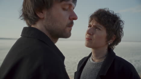 woman emotionally looking at boyfriend beside frozen lake shore