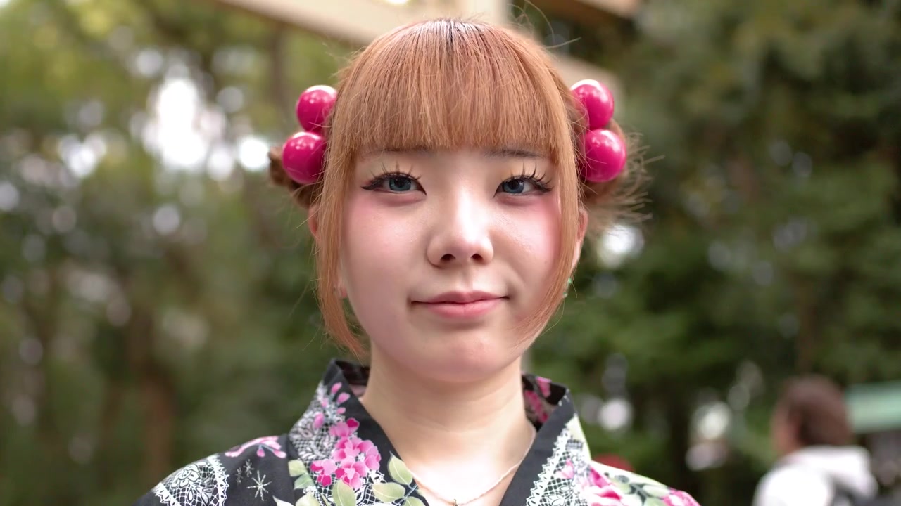 一位穿著花卉浴衣的日本女性站在神社鳥居前。