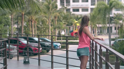 joven turista con pantalones cortos de moda y camiseta rosa observa las palmeras