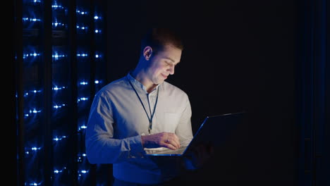 a young technician with a laptop deals with the problem of the server and raises the server broken from hacker attaks