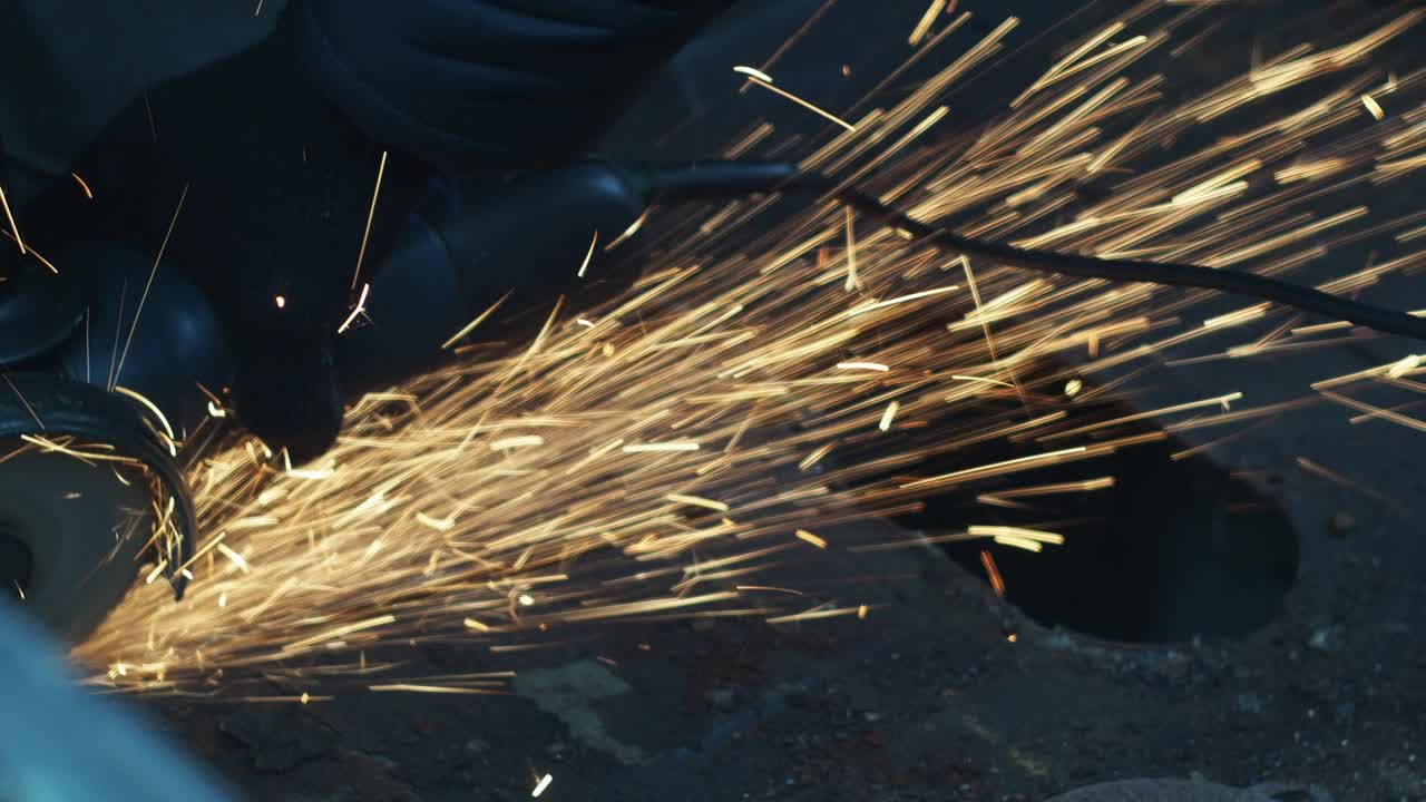 장갑을 입은 남자가 절단 디스크로 금속을 습니다. 각 가루. 금속으로 작업. 화재 스프레이. 수리 가게. 기계 조립 작업의 기계.