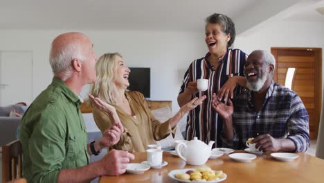 Zwei-Unterschiedliche-Seniorenpaare-Sitzen-Zu-Hause-An-Einem-Tisch-Und-Trinken-Gemeinsam-Tee