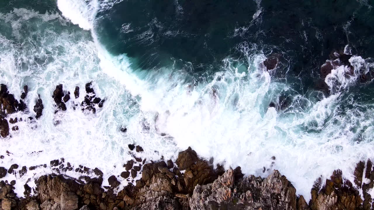 Onde dell'Oceano Atlantico che si infrangono contro la costa rocciosa frastagliata. Ripresa slider dall'alto con drone