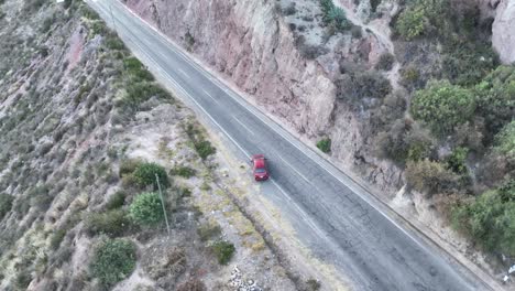 Drone-flight-view,-chasing-red-car-on-the-highway-to-Urubamba