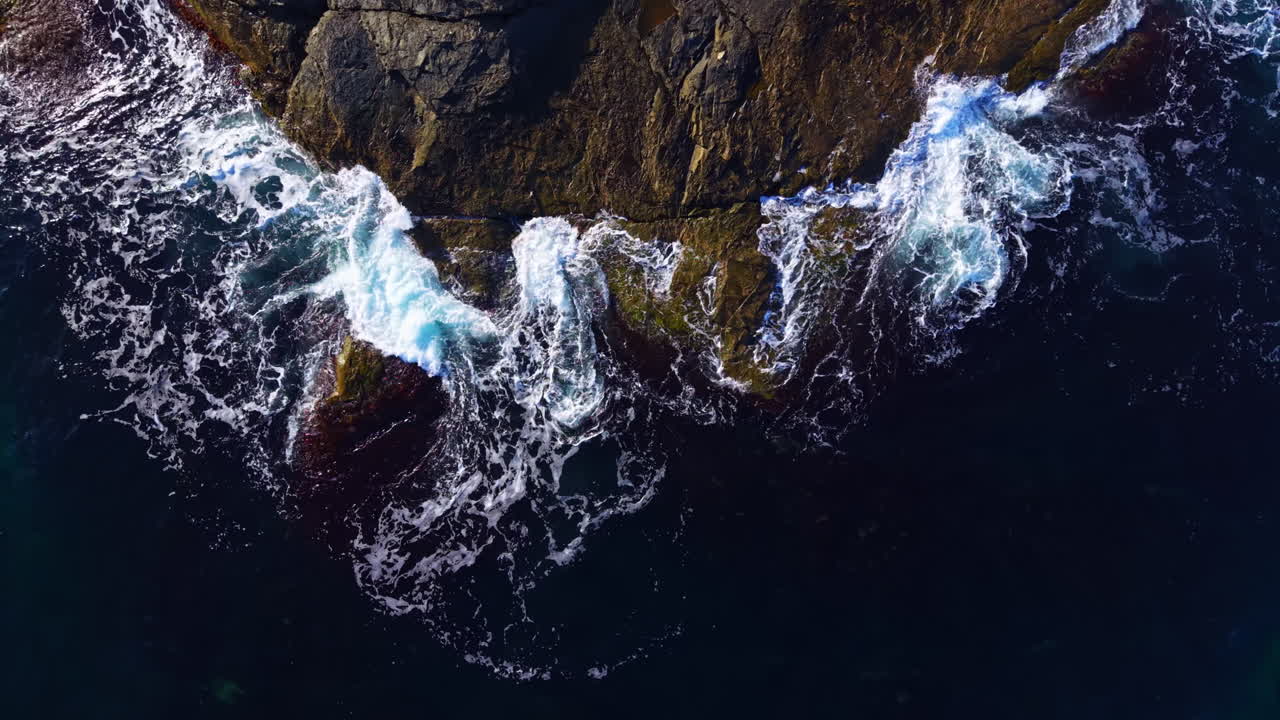 Waves crash against rugged rocks along the coastline at dawn, creating a captivating dance of nature's power and beauty