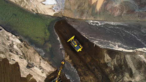 a bulldozer restoring the original course of a river after heavy weather