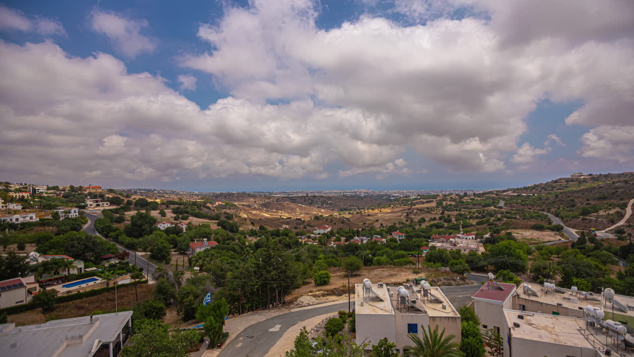 el lapso de tiempo de las nubes cúmulo barriendo los cielos azules sobre una pequeña ciudad en chipre