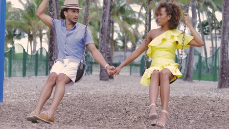 Couple-holding-hands-on-swing