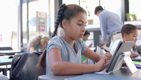biracial girl focused on her tablet at school in the classroom