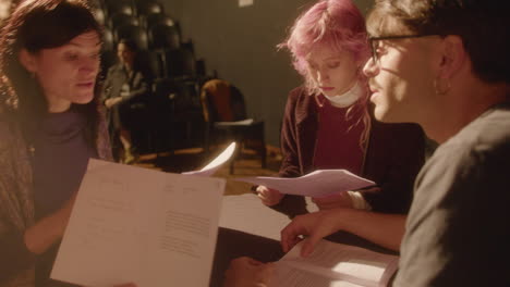 drama students reading play scripts on theater stage