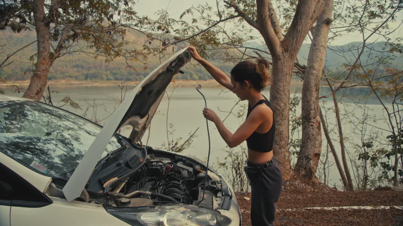 Woman fixing a car by the lake and woman walking on the road in the forest.