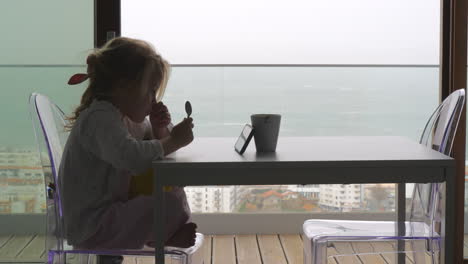 little kid waiting for breakfast and watching videos on the phone