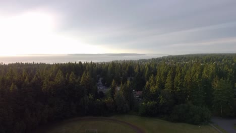 Aerial-of-football-field-in-wooded-neihborrhood-above-the-Puget-Sound,-Edmonds,-WA