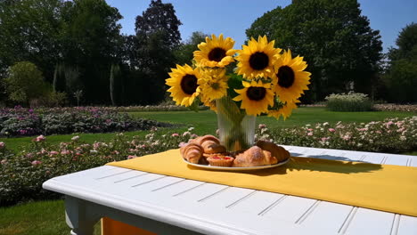 breakfast in a sunny garden with sunflowers and croissants