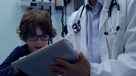 vista frontal de un joven médico asiático y un paciente caucásico usando una tableta digital en la clínica 4k