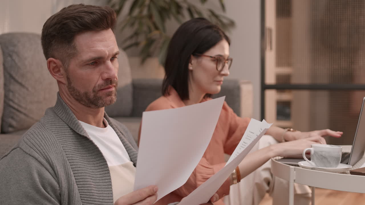 Woman Using Laptop and Man Reading Documents