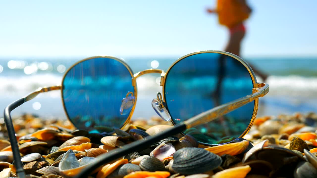 солнцезащитные очки, оставленные на пляже с ракушками, сосредоточьтесь на ракушках.