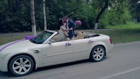 handsome fiance kisses bride in celebratory convertible