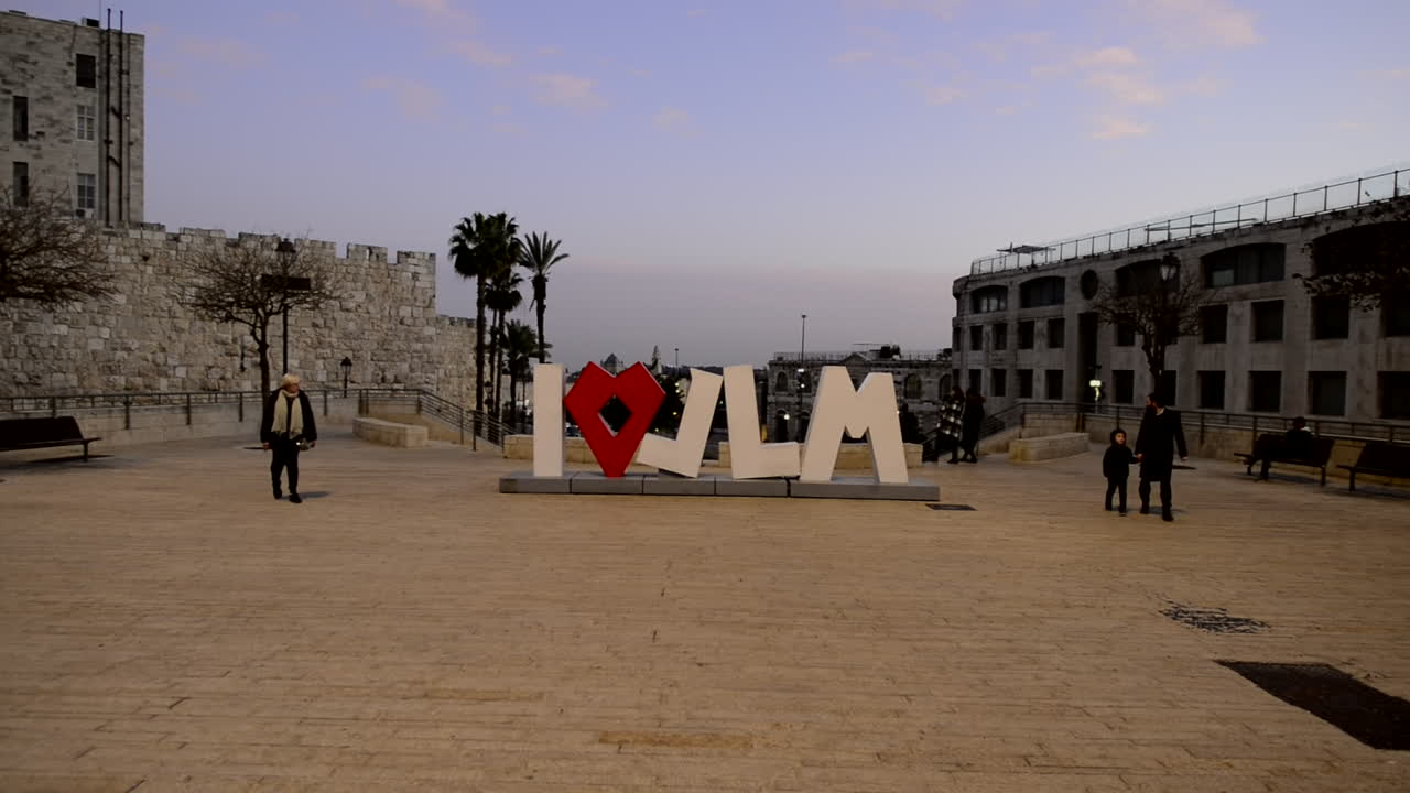 I love Jerusalem city sign letters at pink sunset in Hebrew language. Jewish people walk street. Israel