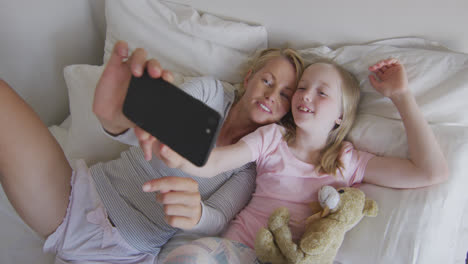 Vista-General-De-La-Mujer-Caucásica-Y-Su-Hija-Tomando-Selfie-En-La-Cama