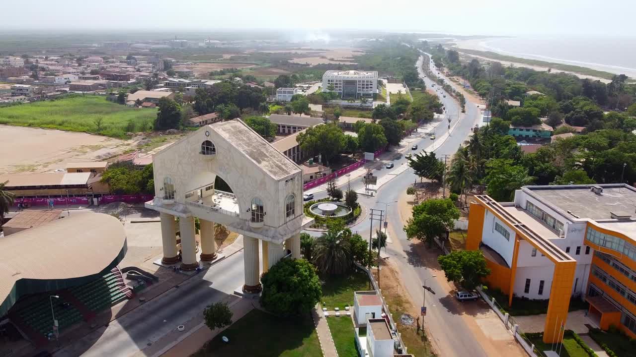 vista cinematográfica del avión no tripulado volando hacia el arco del 22 de julio en la entrada de banjul, gambia - áfrica occidental