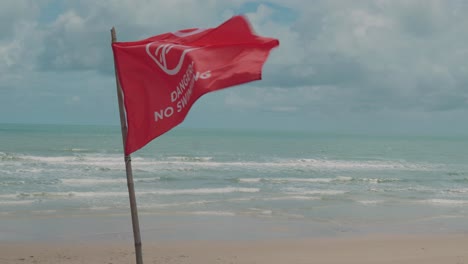 Cierre-La-Bandera-De-Advertencia-En-La-Playa,-La-Bandera-Roja-Se-Balancea-En-El-Viento,-No-Hay-Zona-Para-Nadar,-Horizonte-Marino