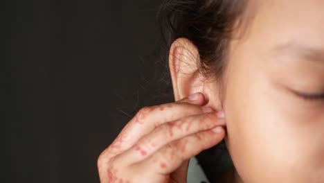 close-up of a child's ear with henna on their hand