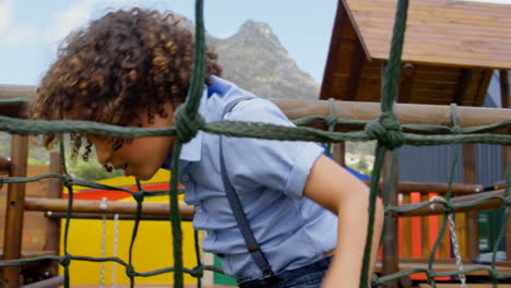 in school, biracial boy with curly hair is climbing a rope structure