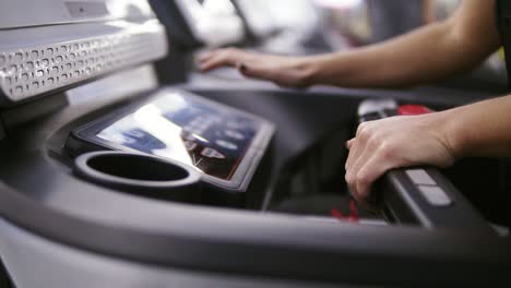 Woman-bodbuilder-setting-up-a-program-and-timer-on-treadmill-set-at-the-gym-preparing-to-start-jogging