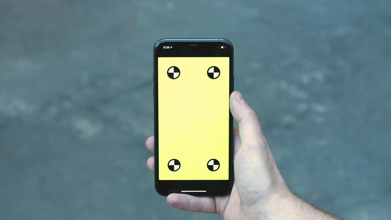 Man's hand holding smartphone with green mock-up chroma key screen