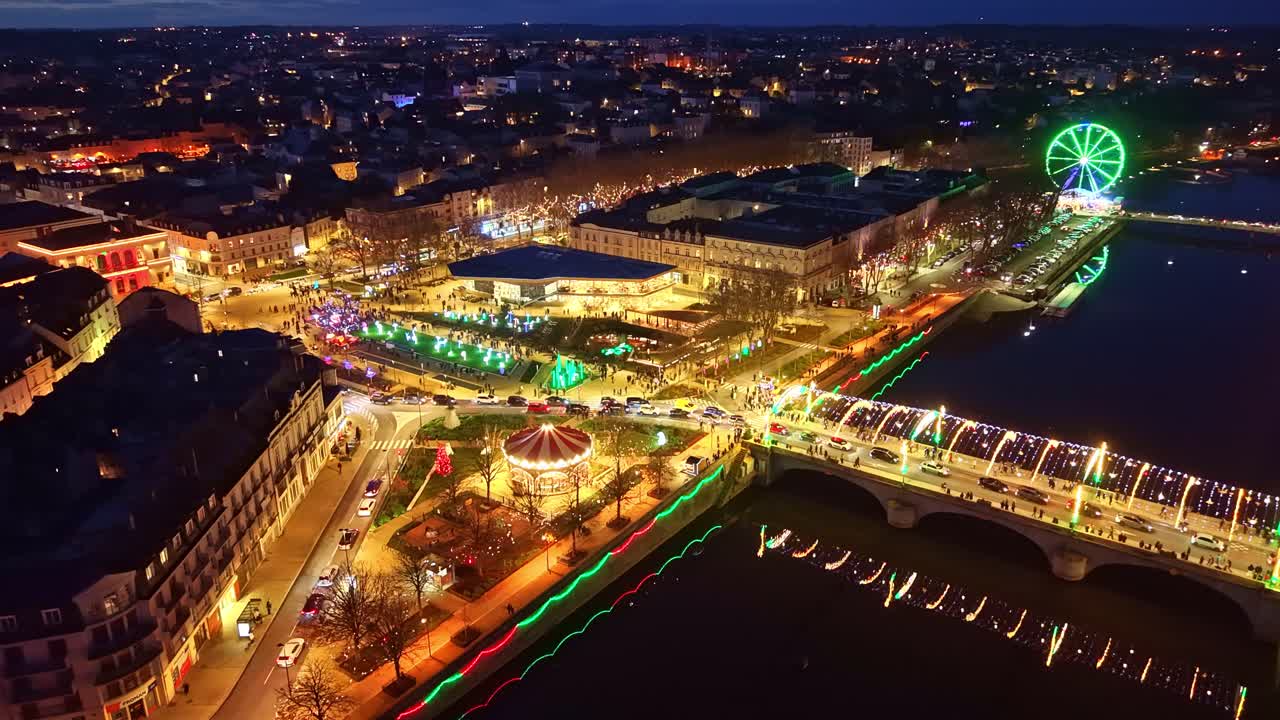 Drone arc over Laval’s Christmas lights, showing Pont Aristide Briand, the Ferris wheel, reflections on the Mayenne, the funfair and festive streets