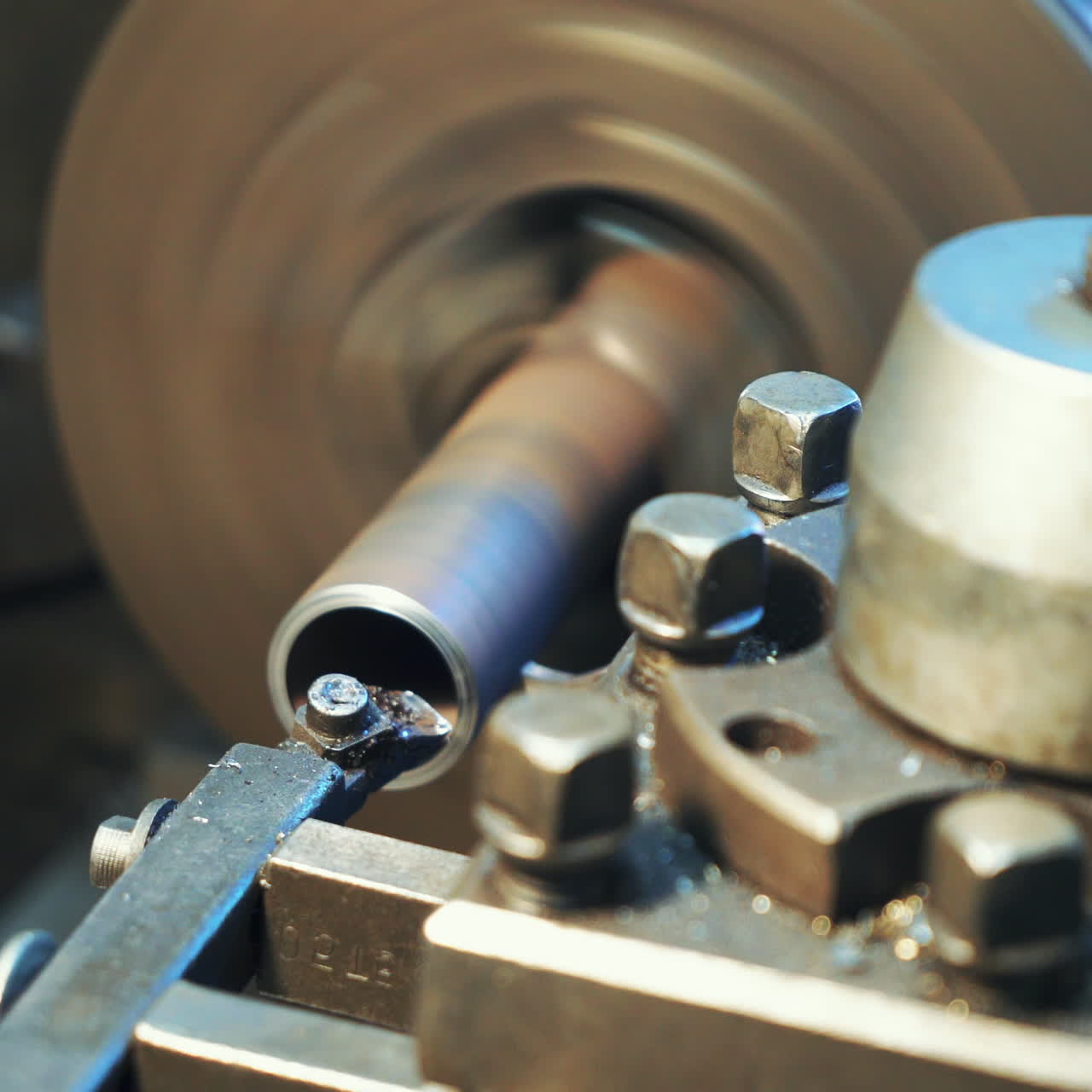 A metal part rotates and sharpeners on the lathe in the workshop in the manufacturing. Close-up.