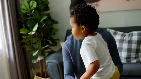 vista frontal de un joven padre negro jugando con su hijo en la vida de una casa cómoda 4k