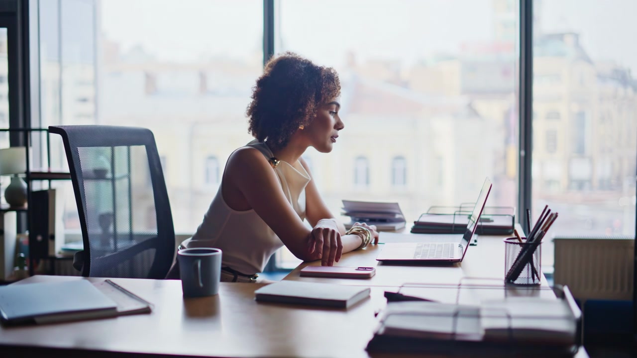 Businesswoman starting workday sitting desk opening laptop in modern office