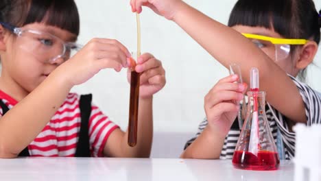 children are learning and doing science experiments in the classroom. two little sisters playing science experiment for home schooling. easy and fun science experiments for kids at home.