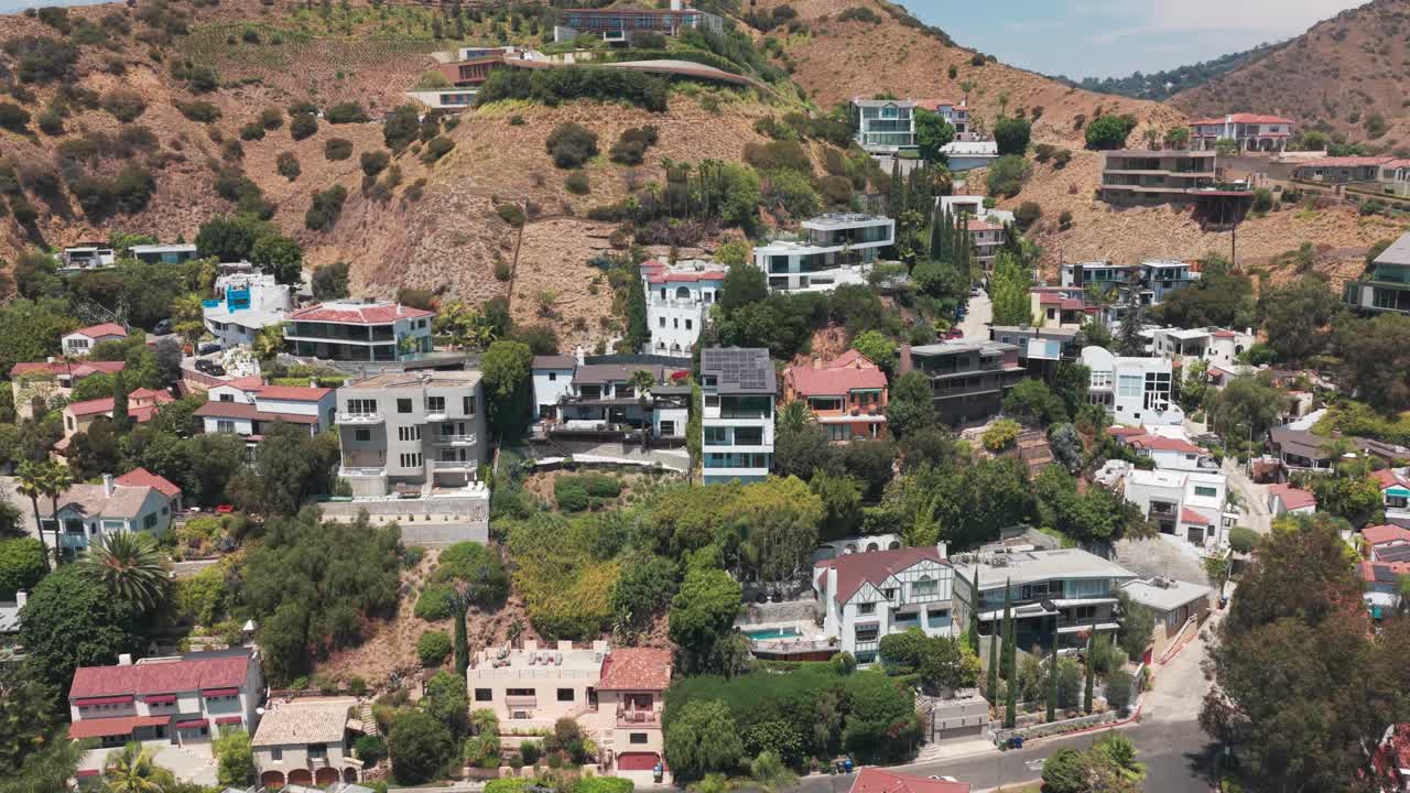 Wide aerial push-in shot of hillside homes in the affluent Hollywood Hills neighborhood of Los Angeles, California. 4K