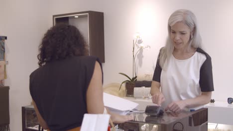 friendly female cashier operating payment process on luxury store