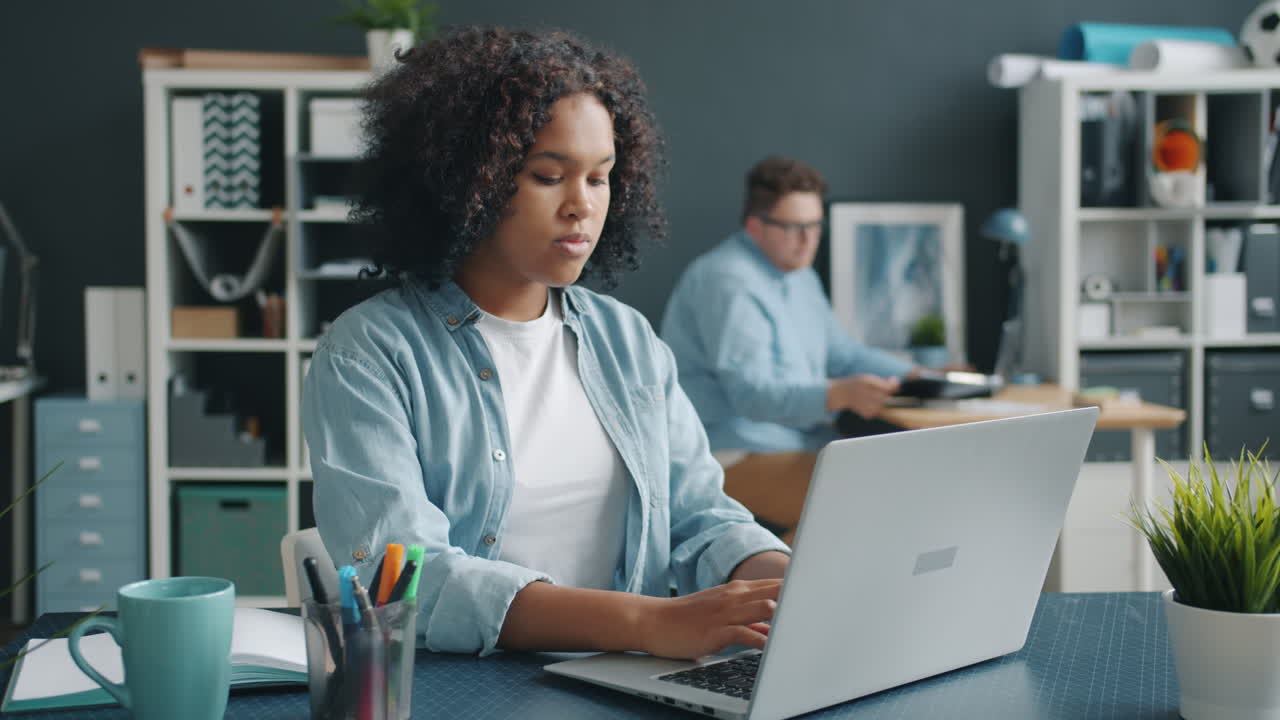 Two colleagues working together on a laptop in a modern office