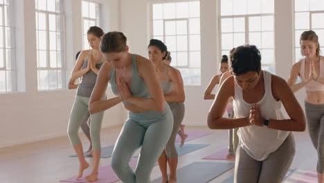 yoga class instructor teaching prayer pose to beautiful group of women enjoying healthy lifestyle exercising in fitness studio at sunrise