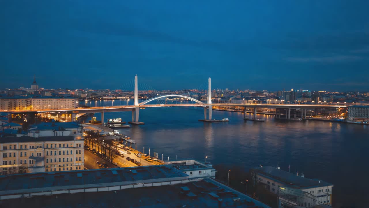 Night view of a modern cable-stayed bridge spanning a river in a lit-up city
