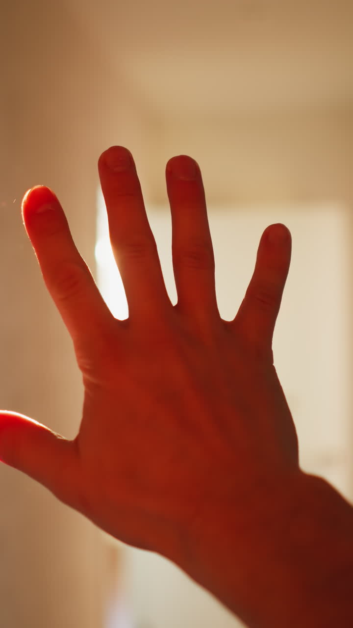 pov de una persona que protege los ojos de la luz solar brillante que entra por una ventana, con un fondo borroso
