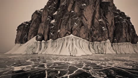 majestic rock formation with ice skirt on cracked frozen lake