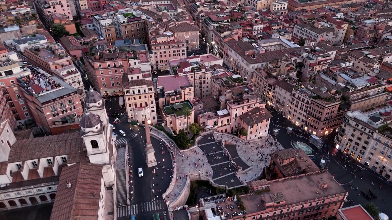 Folk beveger seg over Piazza di Spagna og Spansketrappen mens en drone svever over de omkringliggende kveldsbykvartalene