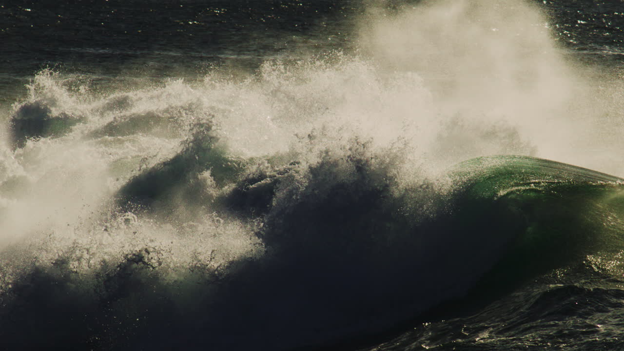 Dark crashing wave barrels forward with glowing mist and deep shadow texture in slow motion
