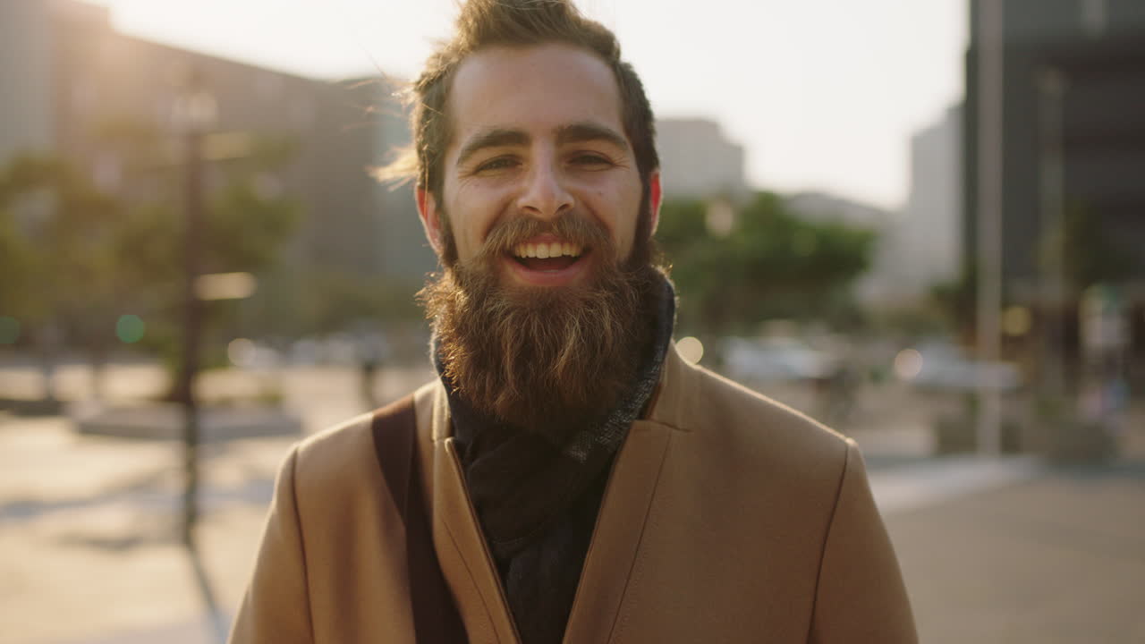 portrait of happy young bearded hipster man smiling cheerful enjoying city urban lifestyle commuting