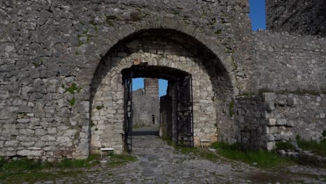 entering the gate of ancient fortress with stone walls and cobblestones, following shot